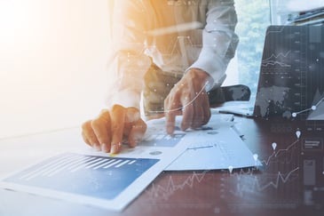 business documents on office table with smart phone and digital tablet and graph financial with big data diagram and man working in the background